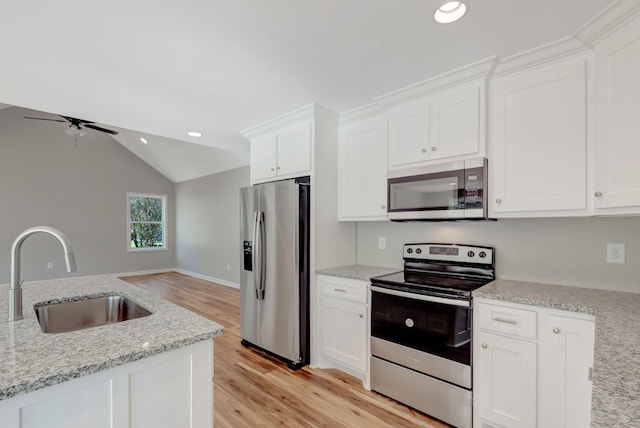 kitchen with light stone counters, stainless steel appliances, sink, and white cabinets