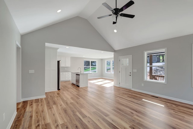 unfurnished living room with sink, high vaulted ceiling, ceiling fan, and light wood-type flooring