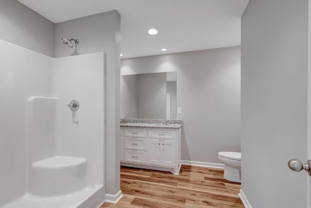 bathroom featuring wood-type flooring, toilet, vanity, and walk in shower