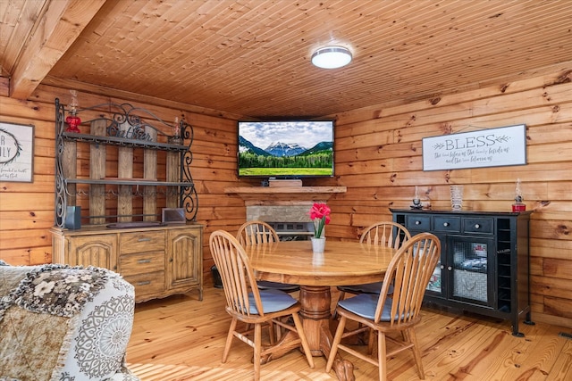 dining room with wood ceiling, light hardwood / wood-style flooring, and wooden walls