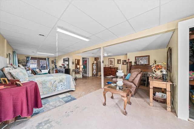 bedroom with a drop ceiling and concrete flooring