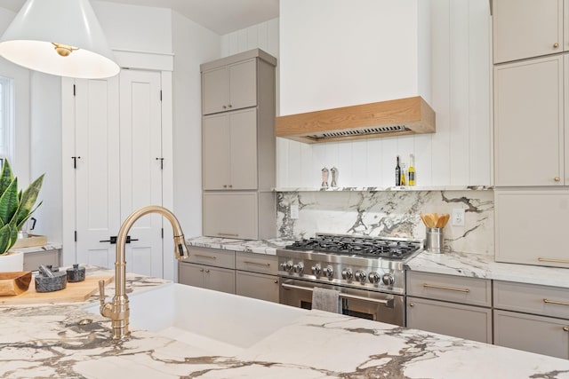 kitchen with high end range, gray cabinets, custom range hood, light stone countertops, and decorative backsplash