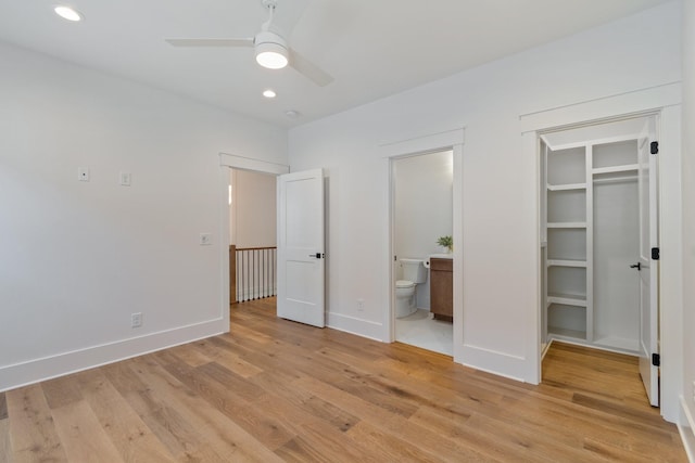 unfurnished bedroom featuring a closet, a walk in closet, connected bathroom, and light hardwood / wood-style flooring