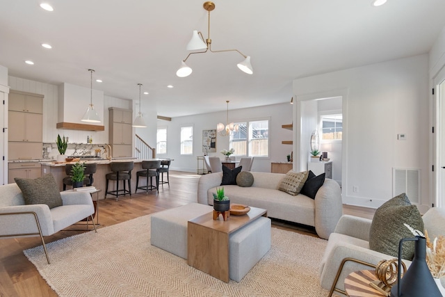 living room with sink, a chandelier, and light hardwood / wood-style floors