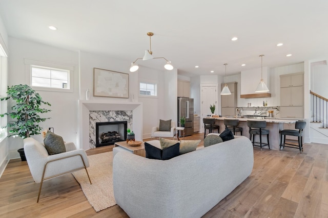 living room featuring sink, a premium fireplace, and light wood-type flooring