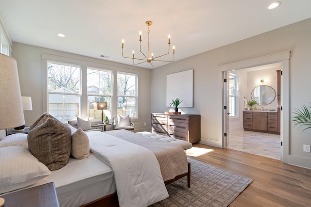 bedroom featuring multiple windows, connected bathroom, an inviting chandelier, and light wood-type flooring