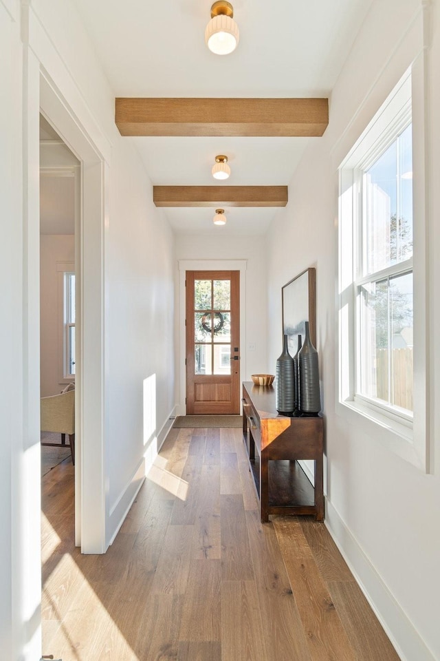 doorway with beam ceiling and light wood-type flooring