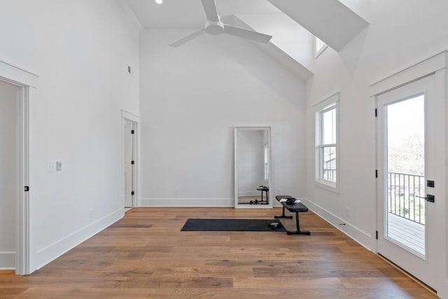 exercise room with a high ceiling, ceiling fan, and light hardwood / wood-style floors