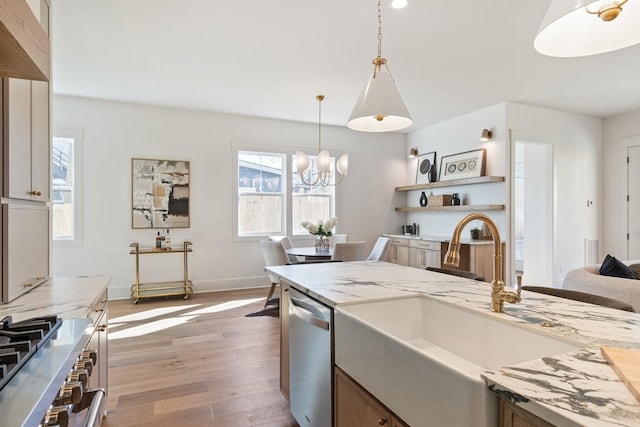 kitchen featuring appliances with stainless steel finishes, decorative light fixtures, sink, dark hardwood / wood-style flooring, and light stone countertops