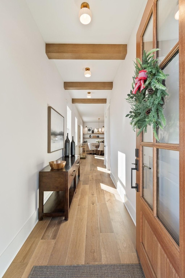 hall featuring beam ceiling and light hardwood / wood-style flooring