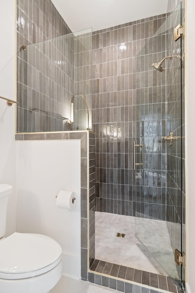 bathroom featuring a shower with door and toilet