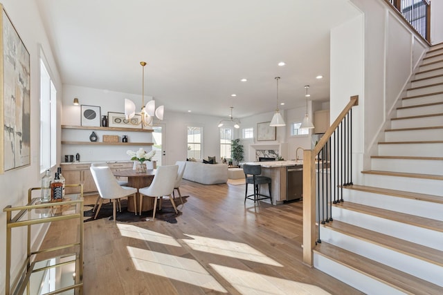 dining room with an inviting chandelier, sink, and light hardwood / wood-style floors