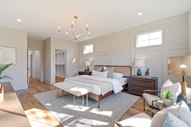 bedroom featuring an inviting chandelier, a walk in closet, a closet, and light wood-type flooring