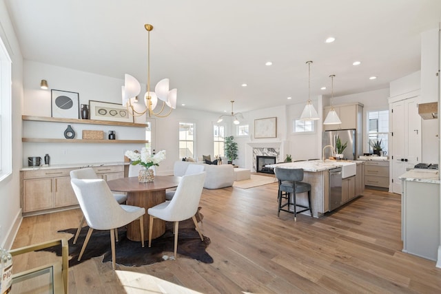 dining room featuring a premium fireplace, sink, a chandelier, and light hardwood / wood-style floors