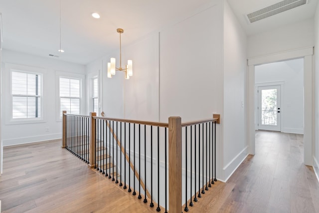 hallway featuring an inviting chandelier and light hardwood / wood-style floors