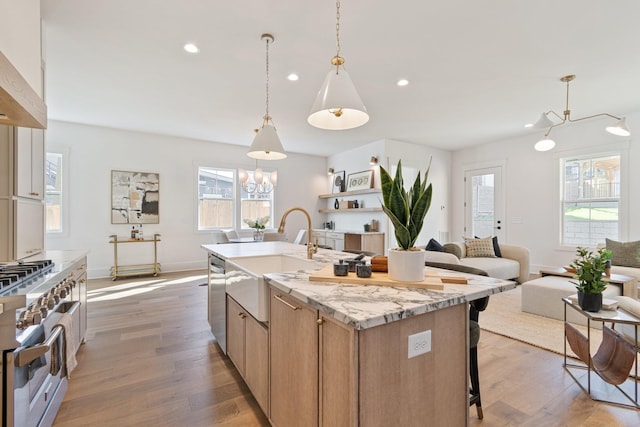 kitchen featuring pendant lighting, sink, appliances with stainless steel finishes, an island with sink, and dark hardwood / wood-style flooring