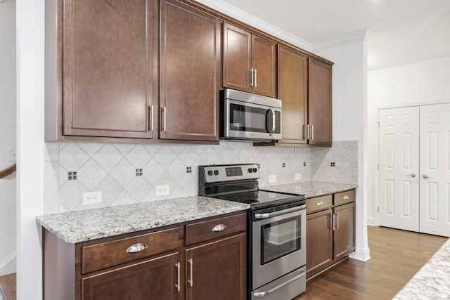 kitchen featuring dark hardwood / wood-style floors, tasteful backsplash, stainless steel appliances, crown molding, and light stone countertops