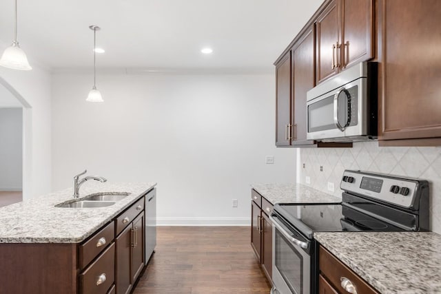 kitchen with sink, decorative light fixtures, stainless steel appliances, a kitchen island with sink, and decorative backsplash