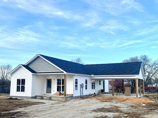 view of front of house with a patio area, covered porch, and a shingled roof