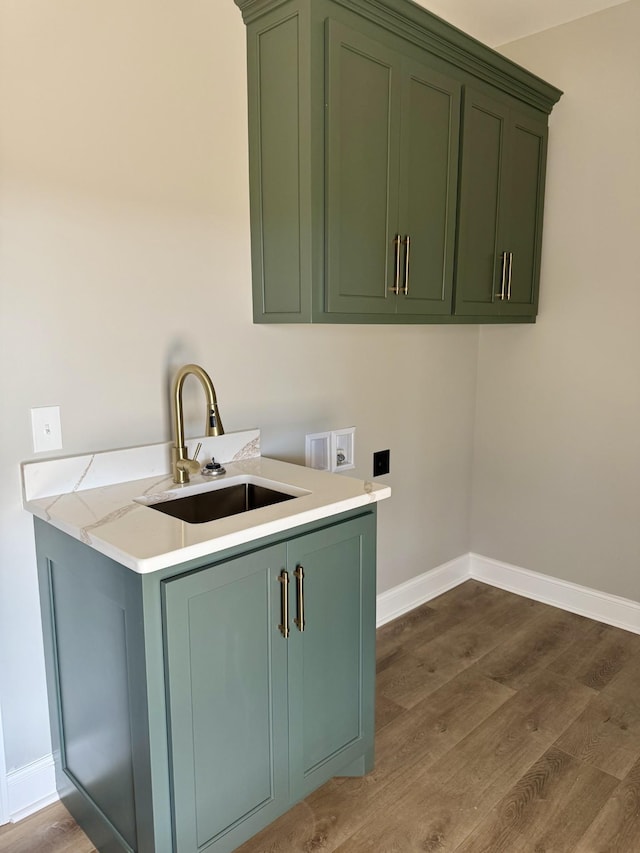 washroom with cabinet space, baseboards, dark wood-style flooring, and a sink