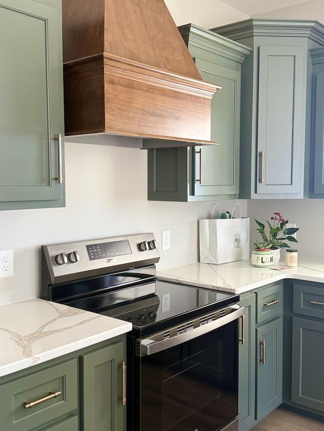 kitchen with electric stove, premium range hood, light stone countertops, and green cabinetry