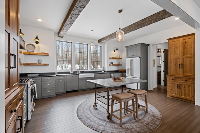 kitchen with high end white refrigerator, a kitchen island, gray cabinets, and range with gas cooktop