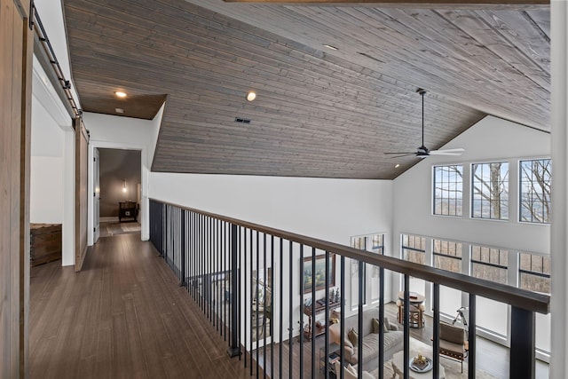 corridor with dark hardwood / wood-style floors, lofted ceiling, a barn door, and wooden ceiling