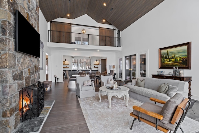 living room with vaulted ceiling, hardwood / wood-style floors, wooden ceiling, and a fireplace