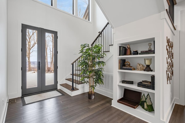 entryway featuring a towering ceiling, dark wood-type flooring, and french doors