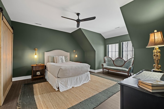 bedroom featuring wood-type flooring, a barn door, ceiling fan, and vaulted ceiling