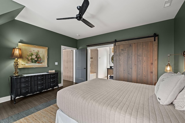 bedroom featuring ceiling fan, a barn door, connected bathroom, and dark hardwood / wood-style flooring