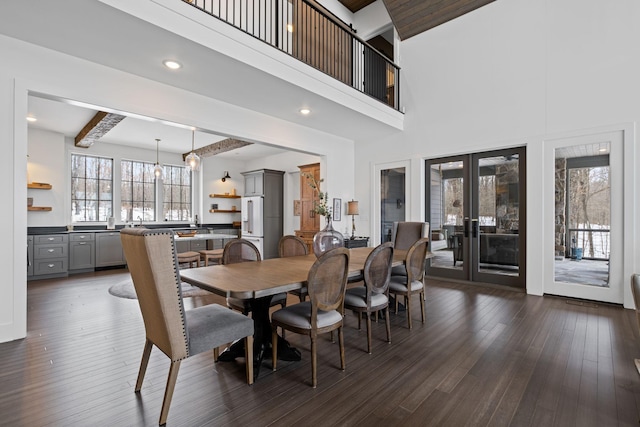 dining room with a towering ceiling, a notable chandelier, dark hardwood / wood-style flooring, french doors, and beamed ceiling