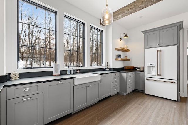 kitchen featuring gray cabinets, high end fridge, sink, and light wood-type flooring