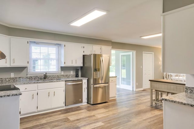 kitchen featuring sink, white cabinetry, light stone counters, stainless steel appliances, and light hardwood / wood-style floors