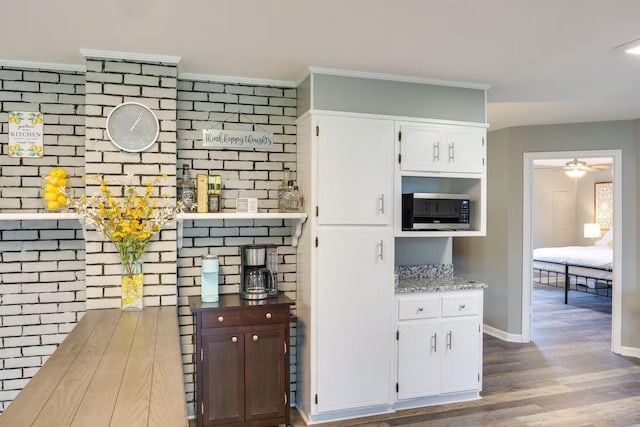 kitchen with wood-type flooring, ornamental molding, white cabinets, and ceiling fan