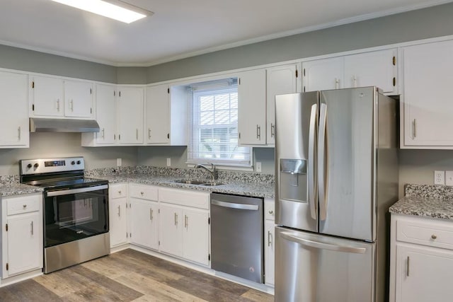 kitchen featuring appliances with stainless steel finishes, white cabinetry, sink, light stone counters, and light wood-type flooring