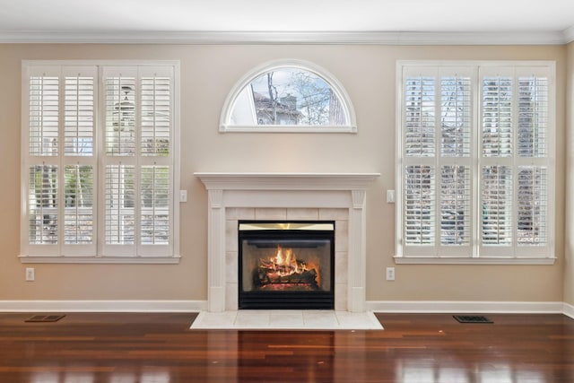 unfurnished living room with a tiled fireplace, wood-type flooring, and ornamental molding