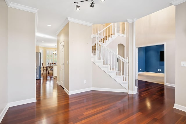 interior space featuring crown molding, wood-type flooring, decorative columns, and a notable chandelier