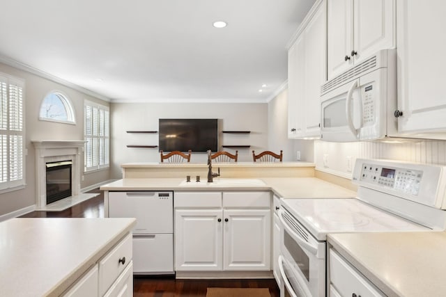 kitchen with a fireplace, sink, white cabinets, ornamental molding, and white appliances