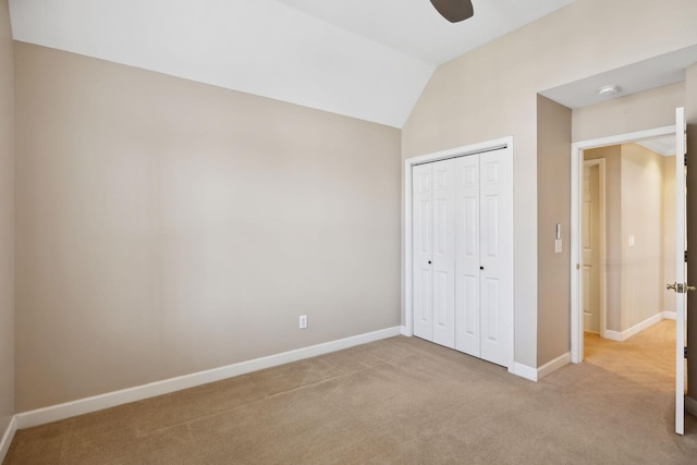 unfurnished bedroom featuring ceiling fan, light colored carpet, lofted ceiling, and a closet