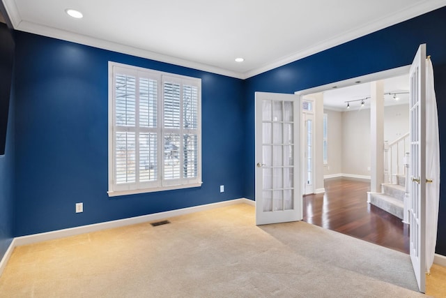 carpeted empty room with crown molding, rail lighting, and french doors