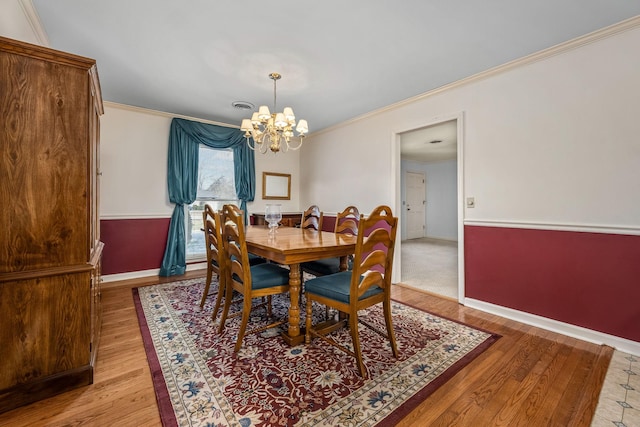 dining space featuring crown molding, a notable chandelier, and light hardwood / wood-style flooring