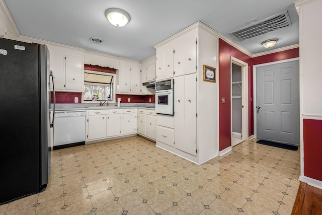 kitchen with crown molding, sink, white cabinets, and white appliances