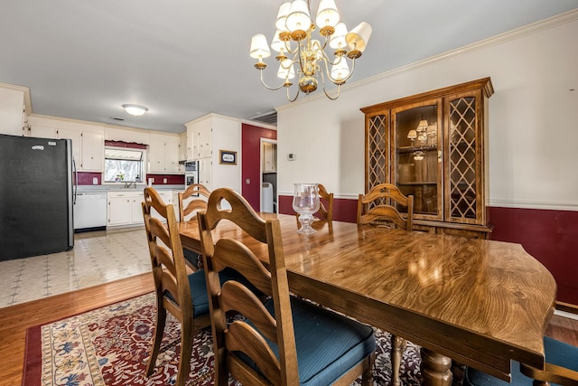 dining area with hardwood / wood-style flooring, ornamental molding, sink, and an inviting chandelier