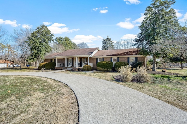 ranch-style home featuring a front lawn and covered porch