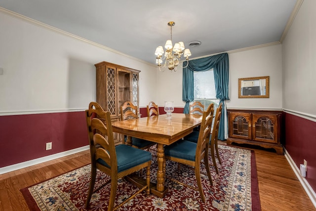 dining area featuring ornamental molding, hardwood / wood-style floors, and a notable chandelier