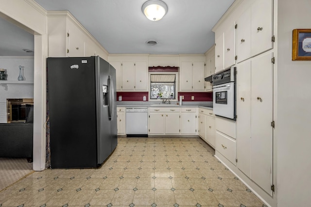 kitchen with sink, white appliances, white cabinets, and a brick fireplace