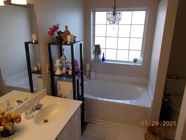 bathroom featuring a notable chandelier, a bathing tub, vanity, and toilet