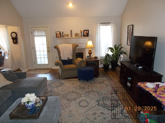 living room with hardwood / wood-style flooring, lofted ceiling, and a tile fireplace