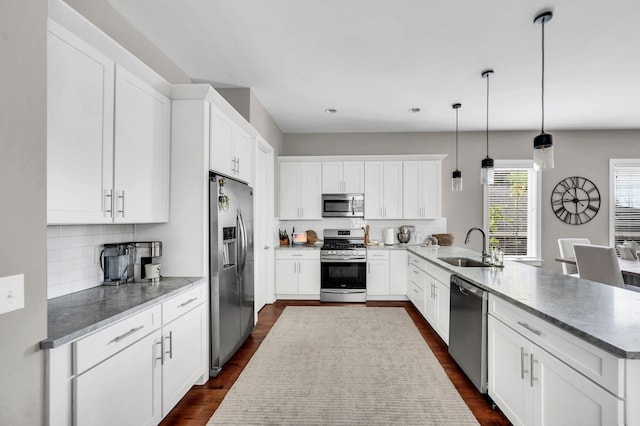 kitchen with sink, white cabinetry, appliances with stainless steel finishes, kitchen peninsula, and pendant lighting